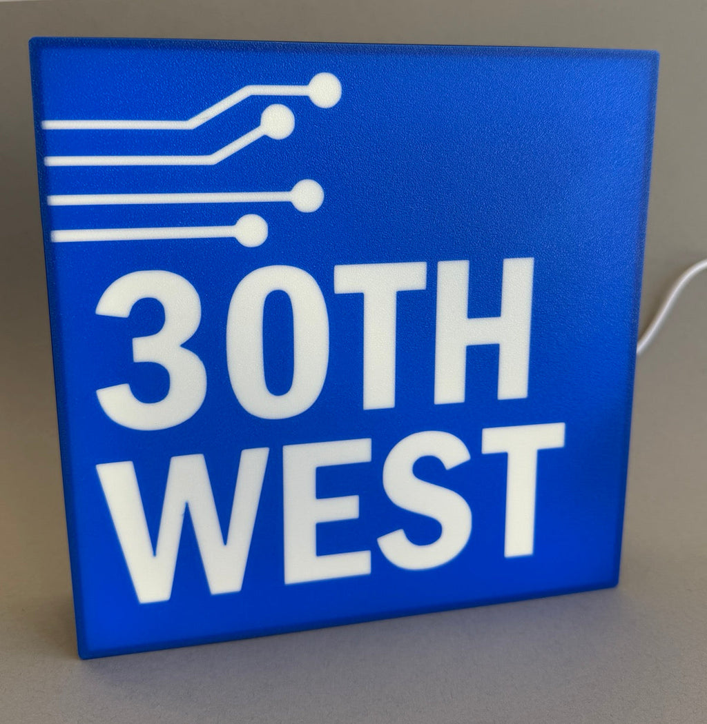 Blue sign with '30th West' text and circuit-like design on a gray background
